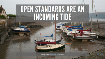 Image of sailboats sitting on sand in a harbour as the tide comes in to refloat them.